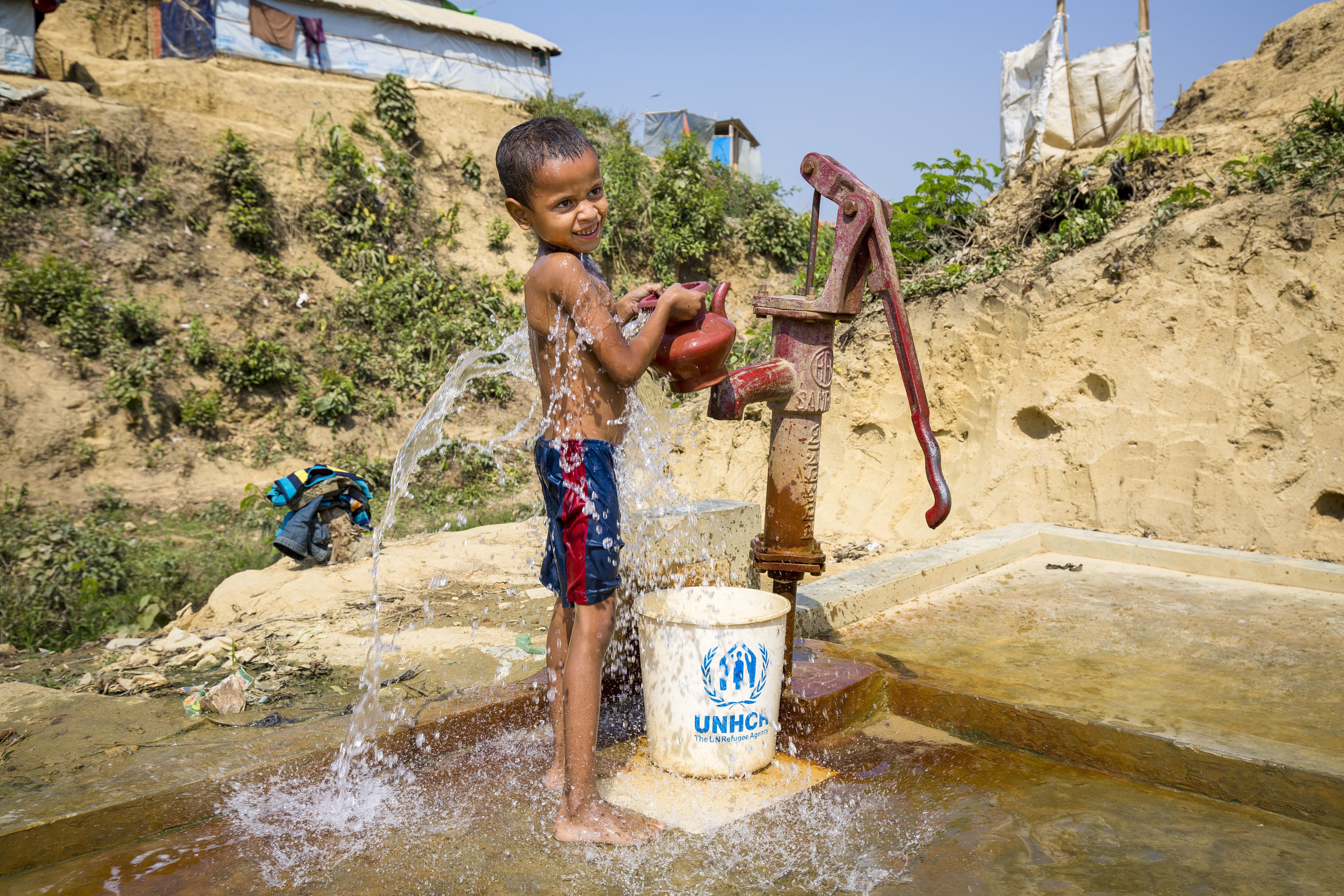 A Rohingya fills a bucket and kettle at a standpipe in Kutupalong camp.