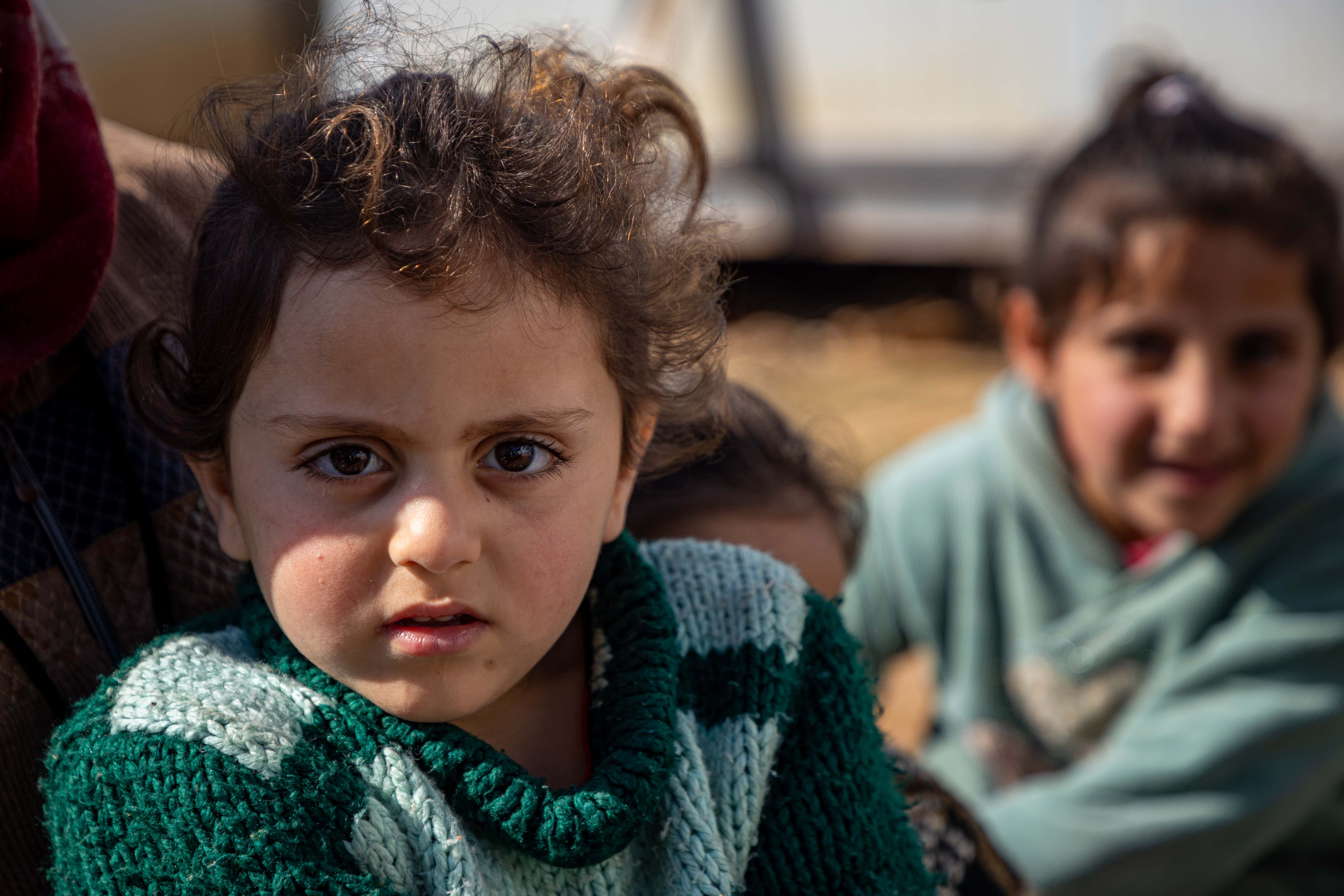 Child wearing a green jumper and looking at the camera