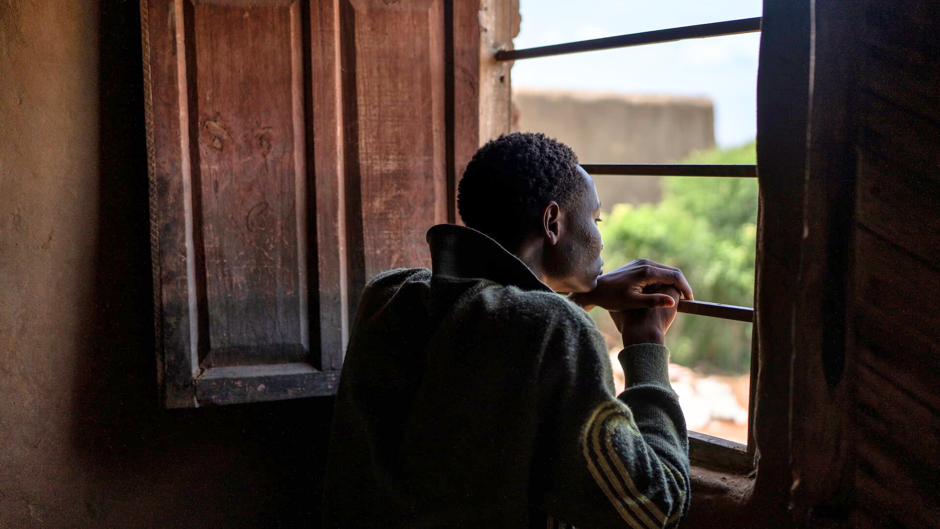 Jules, 17, watches over his sisters and cousins from inside their shelter in Nakivale refugee settlement, Uganda