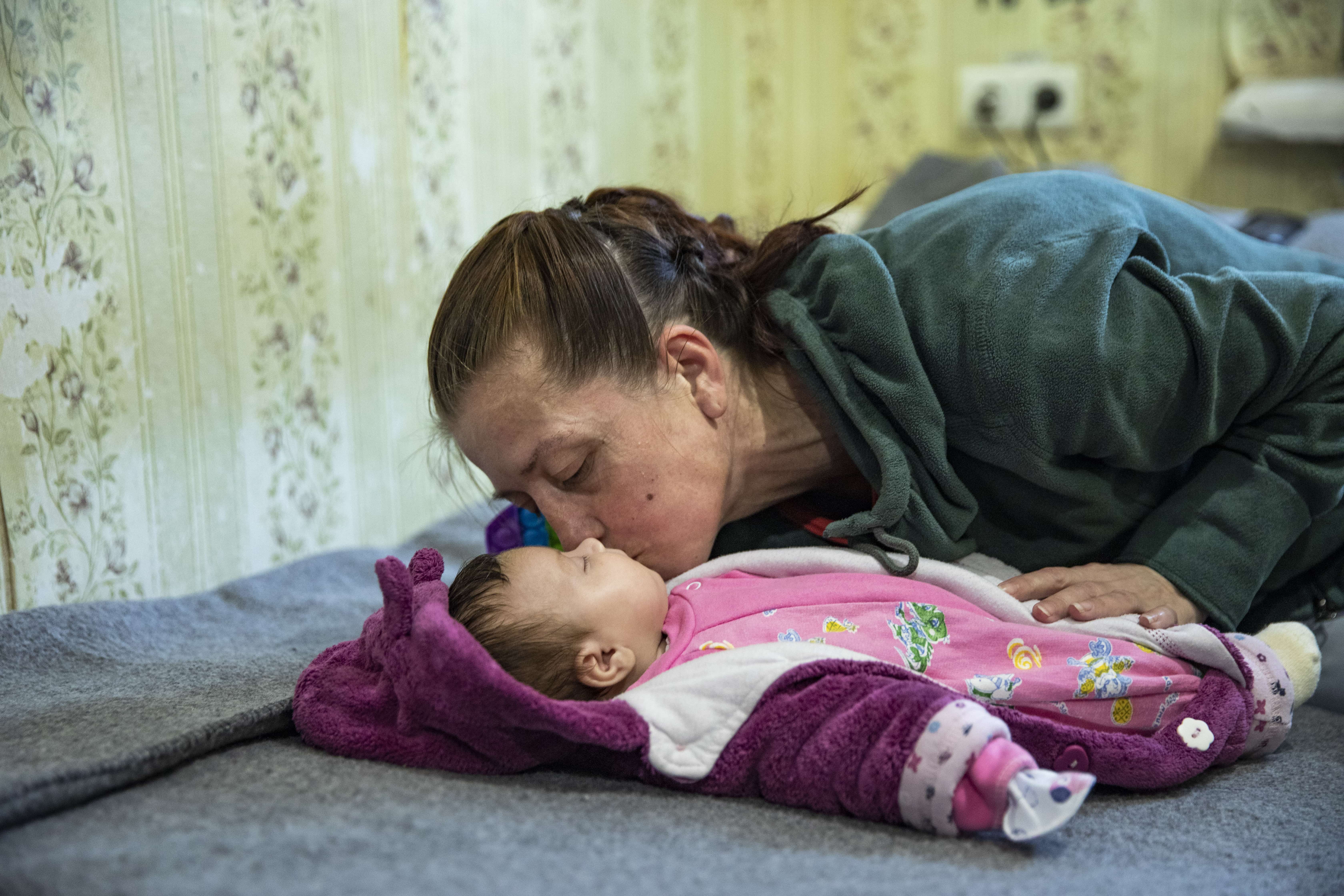 Displaced Ukrainian mother kissing her baby
