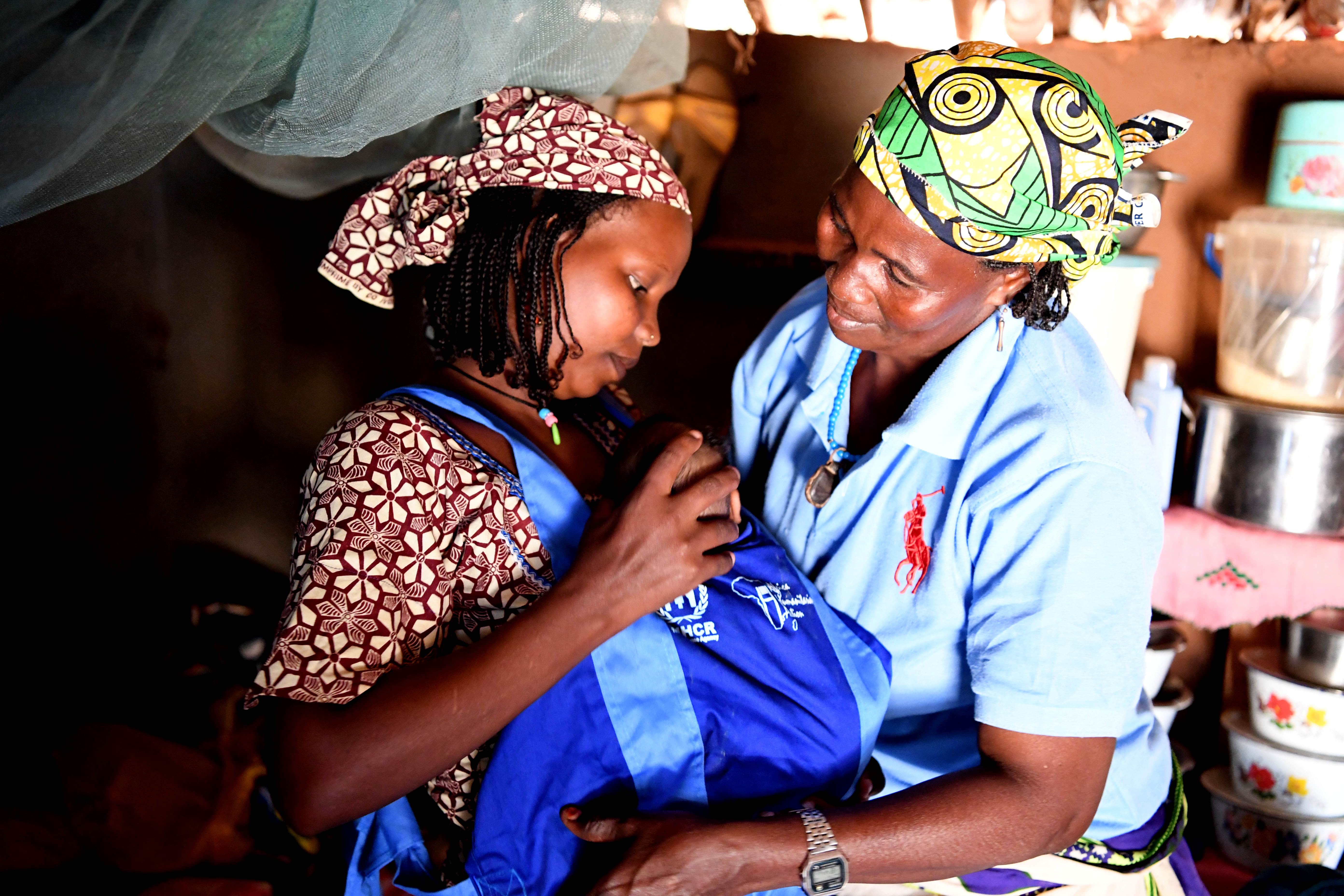A woman helps her daughter in law with the kangaroo scarf in Cameroon.