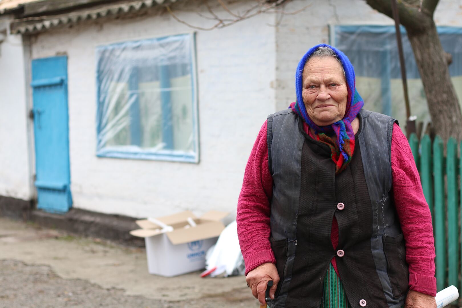 Valentyna, 72, stands outside her home in Ukraine, where she received a heater and insulation materials to help keep her house warm during winter.